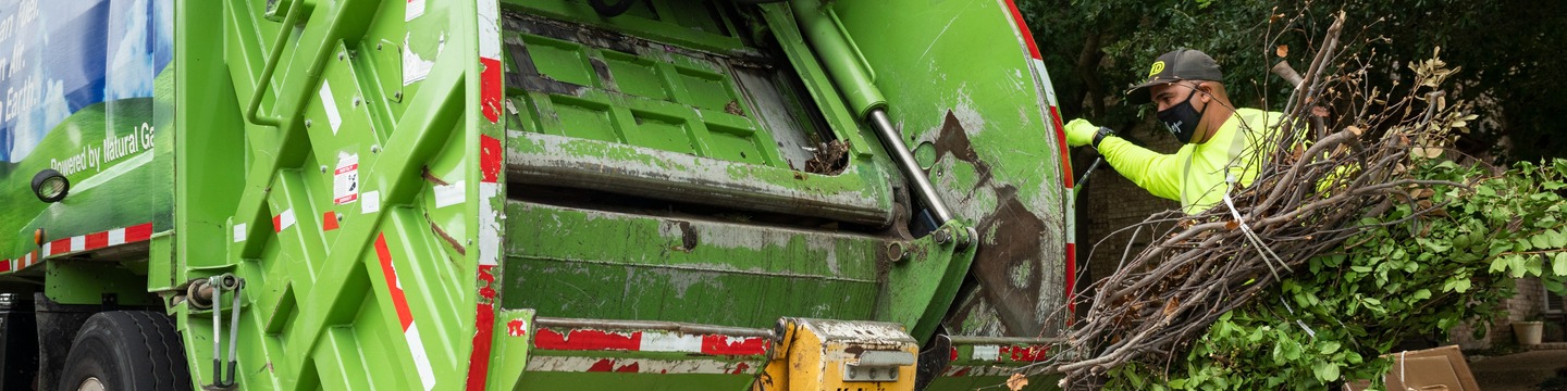 Man loading waste into a garbage truck.